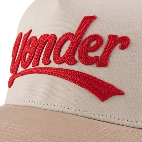 Red chain stitch script on a cream cap