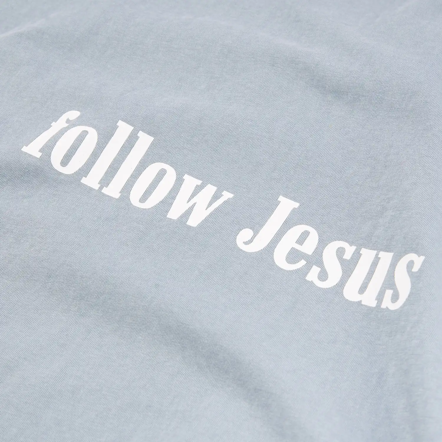 Close-up of white serif screen print on a washed blue-gray T-shirt